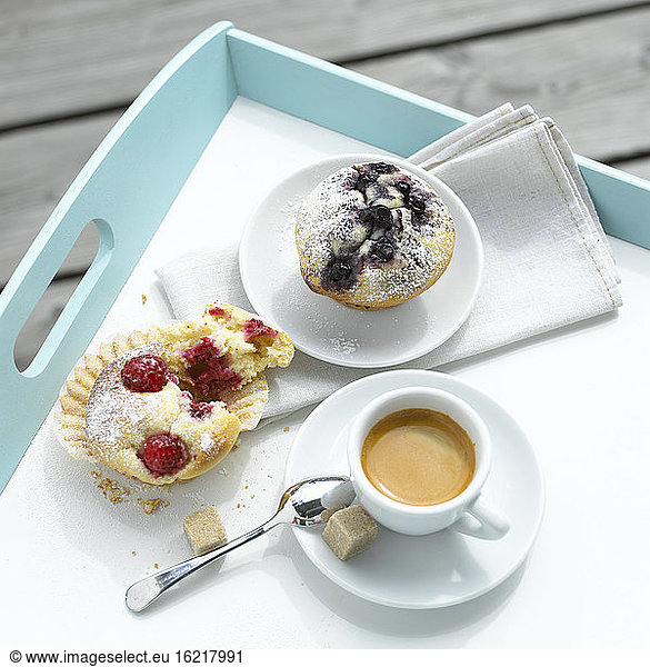 Fruit muffins and a cup coffee on tray  elevated view