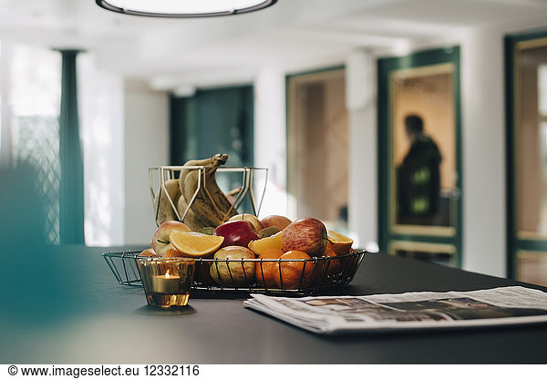 Fruits in basket by newspaper on table at creative office