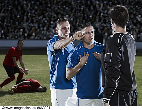 Fußballspieler streiten sich mit Schiedsrichter auf dem Spielfeld