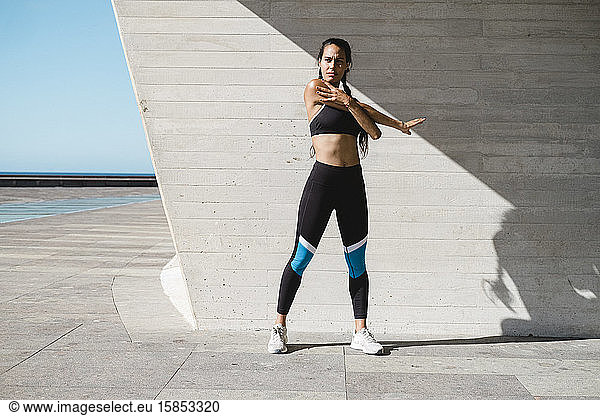 Full body of female athlete stretching arms