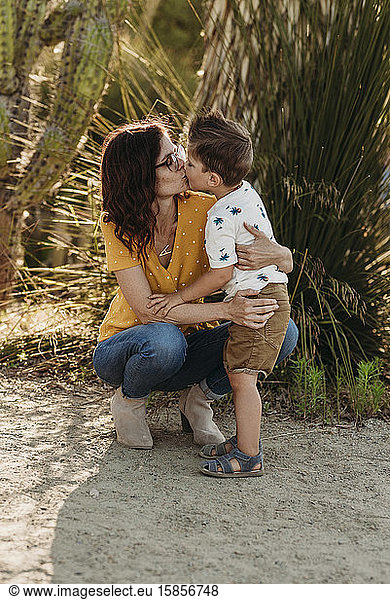 Full body view of mother bending down to kiss preschool aged son