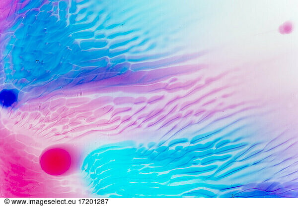 Full frame of blue and pink liquids mixing together