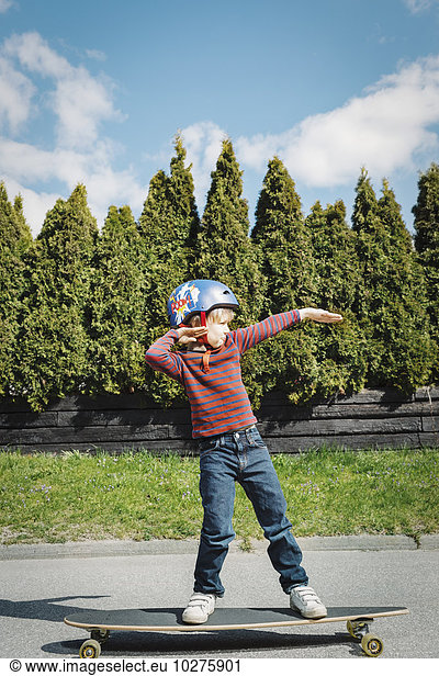 Full length of boy posing while standing on skateboard at yard