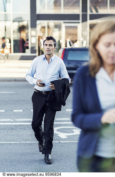 Full length of businessman crossing city street