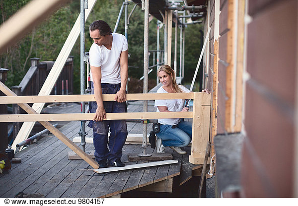 Full length of couple working on porch of house being renovated