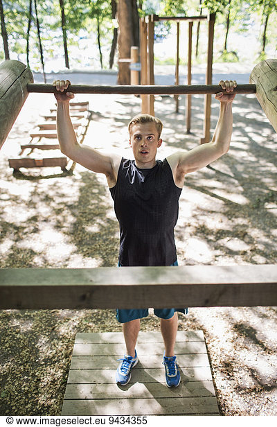 Full length of determined man lifting wooden bar at outdoor gym