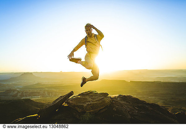 Full length of excited hiker jumping on mountain at Canyonlands National Park