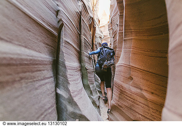 Full length of hiker with backpack canyoneering amidst narrow canyons