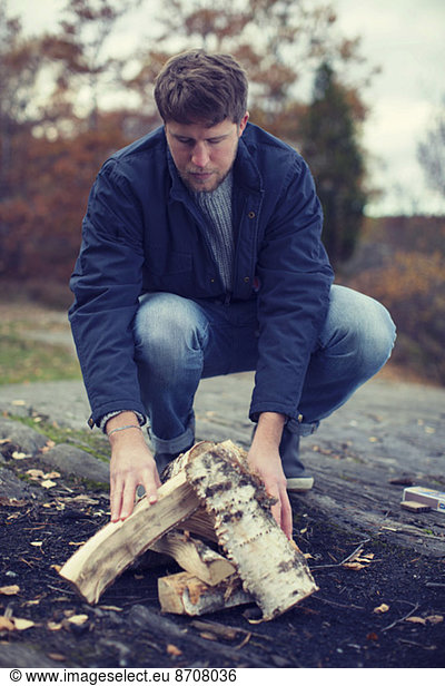 Full length of man arranging wood for bonfire
