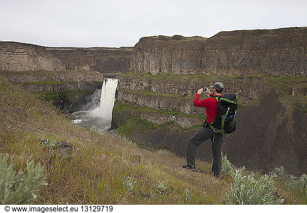 Full length of man photographing waterfall at Palouse Falls State Park