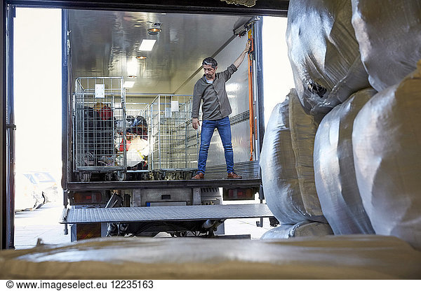Full length of mature male volunteer standing in semi-truck at warehouse