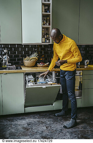 Full length of mid adult man doing dishes in kitchen at home