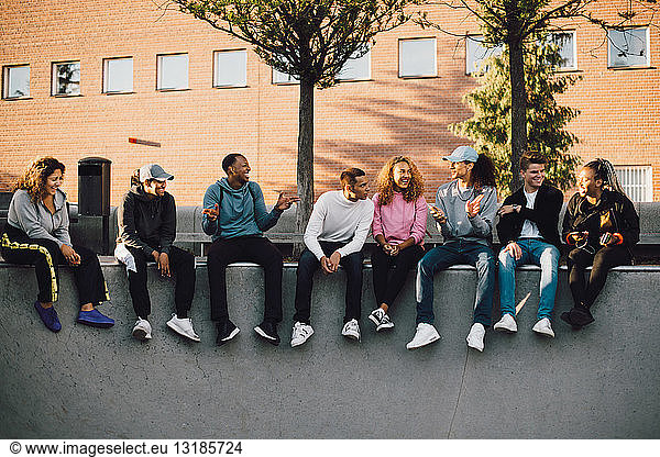 Full length of multi-ethnic friends sitting at skateboard park