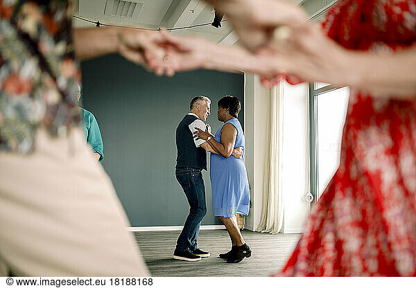 Full length of multiracial senior couple practicing dance in class