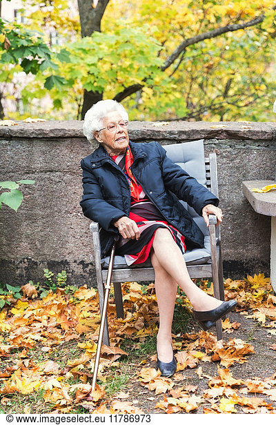 Full length of senior woman sitting on chair in park
