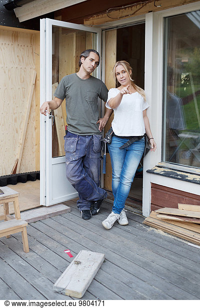 Full length of woman showing something to man at construction site
