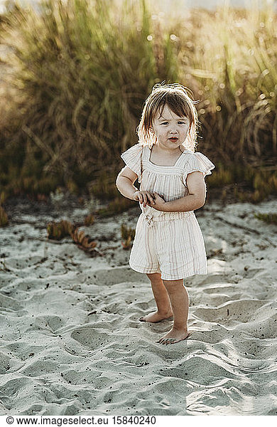 Full length of 2 year-old girl standing at beach during sunset