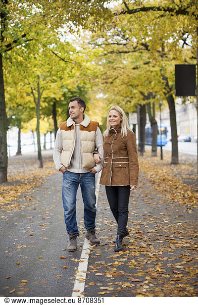 Full length of young couple walking on street during autumn