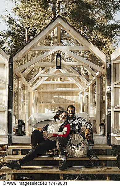 Full length portrait of smiling couple sitting on cottage steps