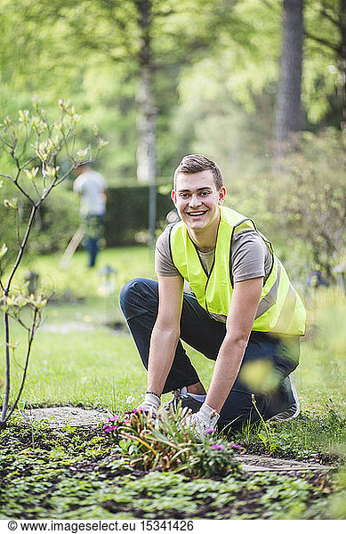 Full length portrait of smiling young man planting at garden