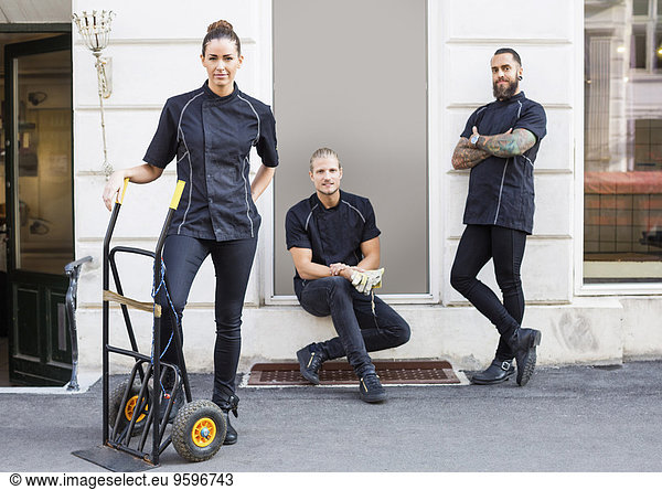 Full length portrait of workers standing outside candy store