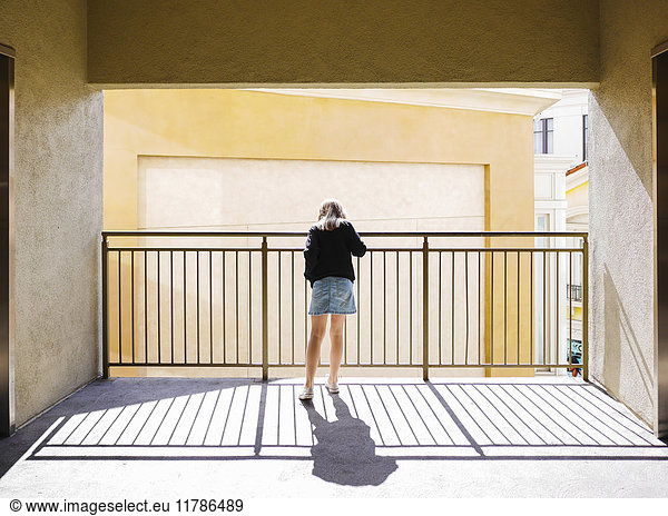 Full length rear view of girl standing by railing