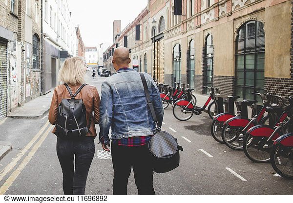 Full length rear view of multi-ethnic couple walking on city street