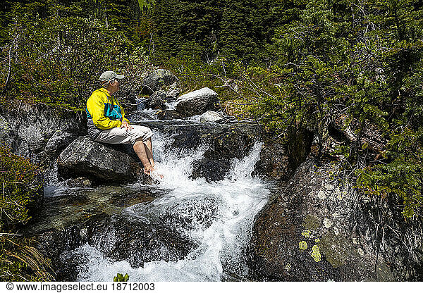 Full length view of women cooling tired feet in a cold alpine river.