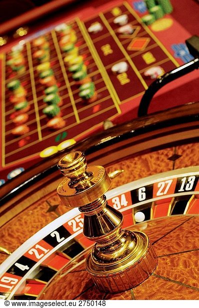 Full roulette table with roulette wheel and gold spinner  table with chips stacked on table as bets made  casino