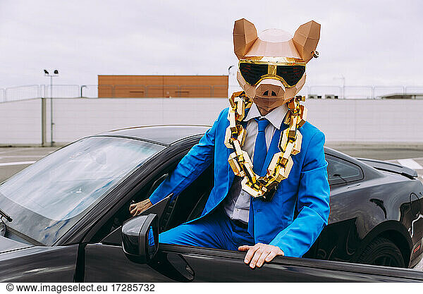 Funny character wearing animal mask and blue business suit getting in car