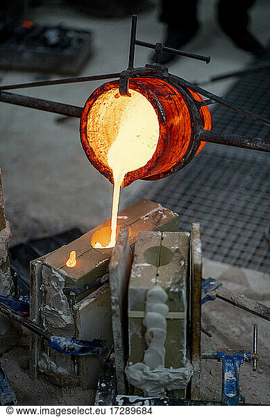 Furnace container pouring melted bronze at foundry