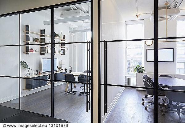 Furniture arranged in modern office seen through windows