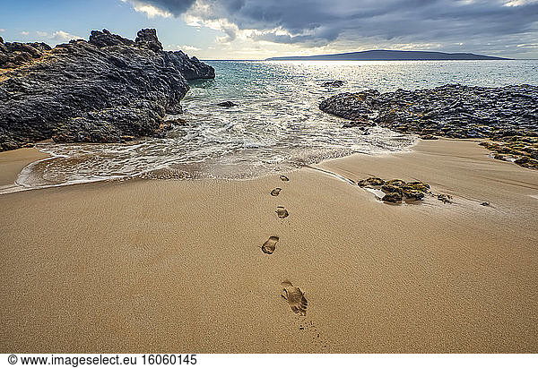 Fussspuren auf dem Sand führen vom Wasser aus zum Ufer  die Küste ist von schroffem Lavagestein gesäumt; Kihei  Maui  Hawaii  Vereinigte Staaten von Amerika