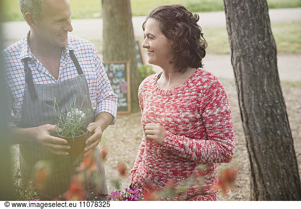 Gärtnerin hilft Frau mit Topfblumen