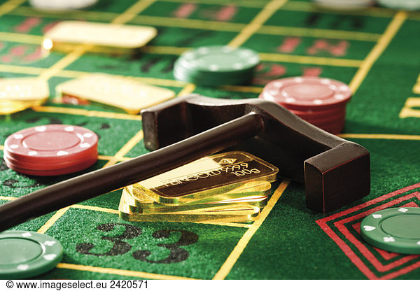 Gambling chips and gold bars on roulette table