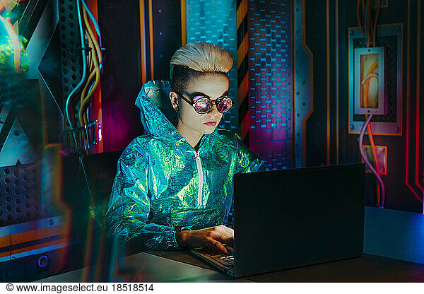 Gamer wearing eyeglasses playing video games on laptop at desk