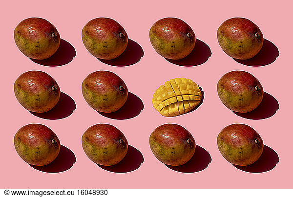 Ganze und eine zerkleinerte Mango Muster auf rosa Hintergrund