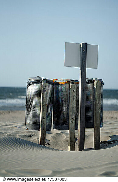 Garbage cans with placard on sand at beach