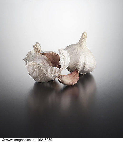 Garlic clove and garlic bulb on coloured background  close up