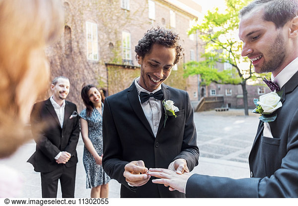 Gay couple exchanging rings during wedding ceremony