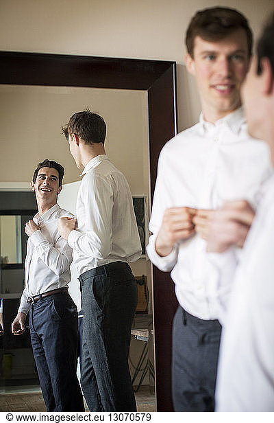 Gay couple looking at each other while getting dressed at home