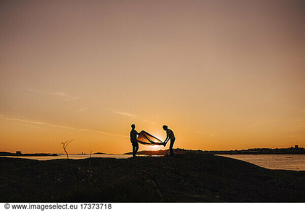 Gay couple preparing tent at lakeshore during camping