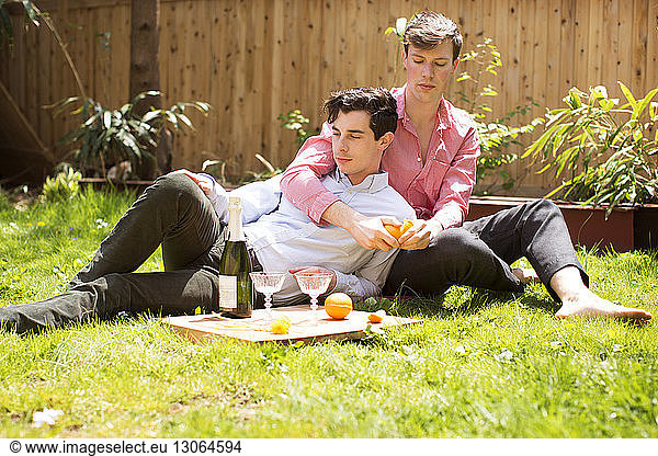 Gay couple relaxing on field in backyard