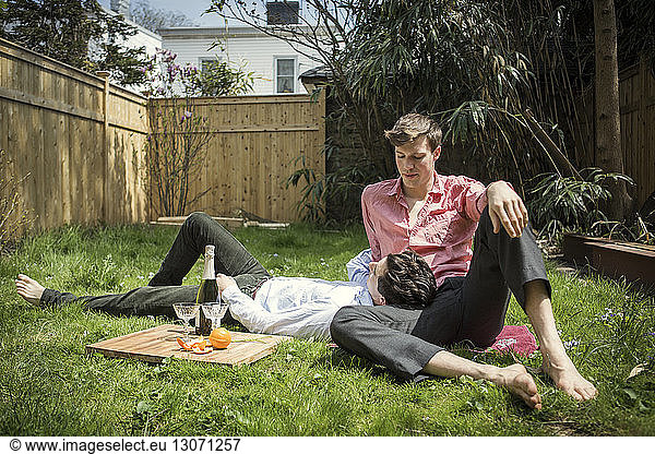 Gay couple relaxing on field in backyard