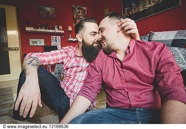 Gay couple rubbing noses in bedroom