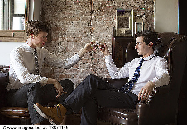 Gay couple toasting tequila shots while sitting at home