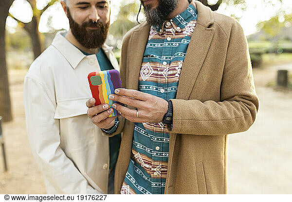 Gay couple using smart phone in park
