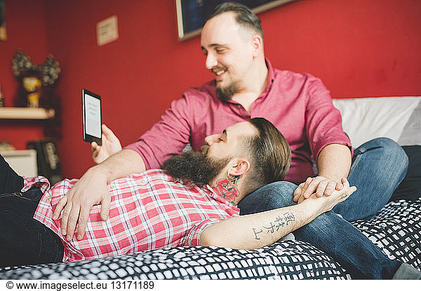 Gay couple using smartphone in bedroom