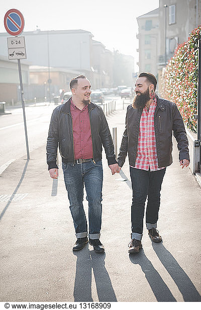 Gay couple walking hand in hand on street
