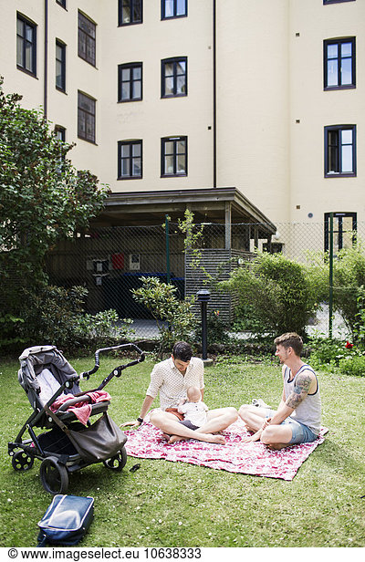 Gay couple with baby girl sitting at yard